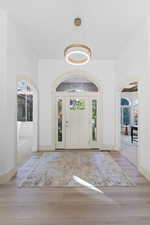 Foyer entrance with arched walkways and light wood-style flooring
