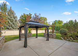 Fenced backyard featuring a patio and a gazebo