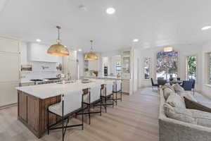 Kitchen with a kitchen bar, recessed lighting, light wood-type flooring, hanging light fixtures, and a large island with sink