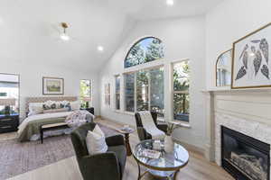 Bedroom featuring high vaulted ceiling, multiple windows, light wood-style flooring, recessed lighting, and a fireplace
