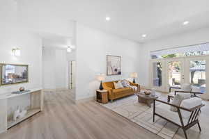 Living room with french doors, light wood finished floors, and recessed lighting