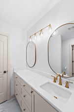 Full bath featuring double vanity and light marble finish floors