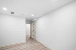 Empty room featuring light wood-type flooring and recessed lighting