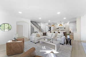 Living area with arched walkways, light wood-style flooring, recessed lighting, and stairway