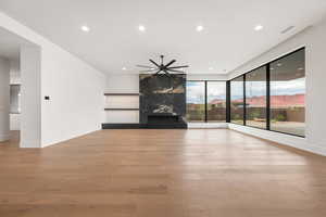 Unfurnished living room featuring light wood-style floors, recessed lighting, a fireplace, a mountain view, and ceiling fan