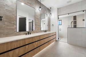 Bathroom with double vanity, tile walls, a shower stall, decorative backsplash, and light tile patterned flooring