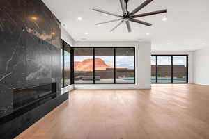 Unfurnished living room with a mountain view, light wood-type flooring, recessed lighting, a fireplace, and a ceiling fan