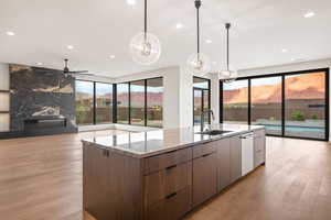 Kitchen with modern cabinets, a mountain view, light wood-style floors, a center island with sink, and light stone countertops