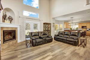 Open floor plan with plenty of natural light, a towering ceiling, light wood-type flooring, and a tiled fireplace.