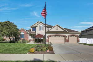 View of front of property featuring brick siding, concrete driveway, stucco siding, and a garage with RV pad.