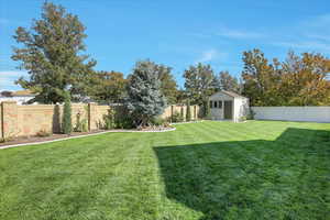Fenced backyard featuring a storage shed.