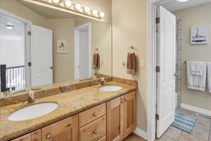 Full bath with light tile patterned floors and double vanity.