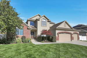 Traditional-style house with stucco siding, brick siding, driveway, and an attached garage