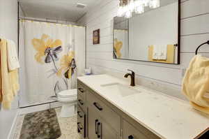 Bathroom featuring vanity, a stall shower, light tile patterned floors, wood walls, and a textured ceiling