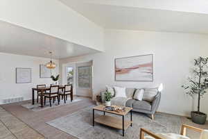 Elegant formal living room features soaring vaulted ceilings and a large window that floods the space with natural light. Seamlessly connected to the formal dining area, this inviting space offers a perfect blend of grandeur and comfort—ideal for entert