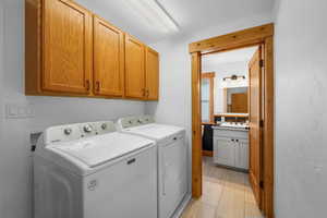 Laundry area featuring cabinet space, washing machine and dryer, and light tile patterned flooring