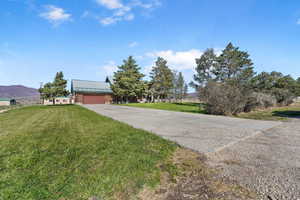 View of front facade featuring a front lawn, a mountain view, driveway, and a garage