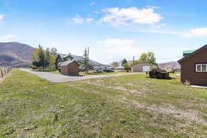 View of grassy yard with a mountain view, an outbuilding, and a detached garage