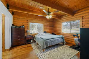 Bedroom with light wood-style flooring, a wood ceiling with exposed beams, and ceiling fan