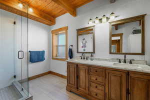 Full bathroom with double vanity, a wooden ceiling with exposed beams, light tile patterned floors, and a stall shower