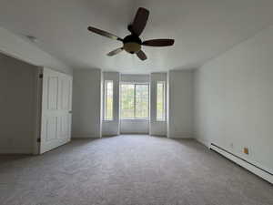 Unfurnished room featuring a textured ceiling, carpet, baseboard heating, and a ceiling fan