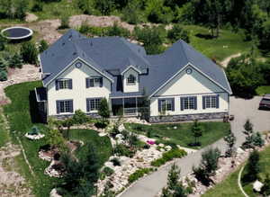 Rear view of property with a yard, stone siding, and a shingled roof