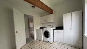 Washroom featuring cabinet space, light floors, washing machine and dryer, and beamed ceiling