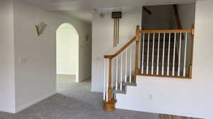 Staircase featuring arched walkways and carpet flooring
