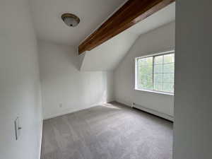 Bonus room with light carpet and a baseboard radiator