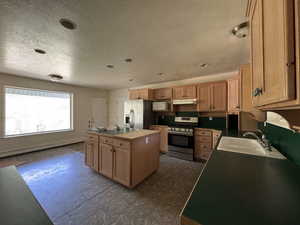 Kitchen with stainless steel appliances, a kitchen island, a baseboard radiator, dark flooring, and a textured ceiling
