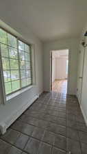 Tiled empty room featuring baseboard heating and baseboards