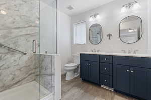 Bathroom with double vanity and a marble finish shower