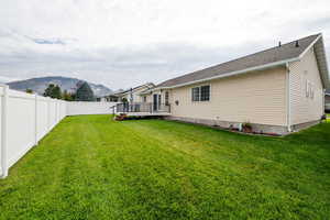 Rear view of house with a deck with mountain view and a fenced backyard
