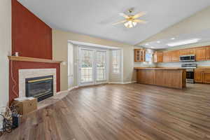Kitchen with open floor plan, a peninsula, lofted ceiling, glass insert cabinets, and a fireplace