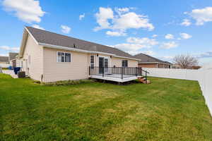 Back of property featuring a deck, roof with shingles, and a fenced backyard