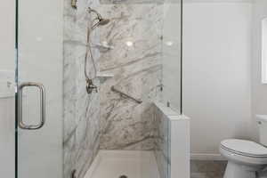 Bathroom featuring a marble finish shower and toilet