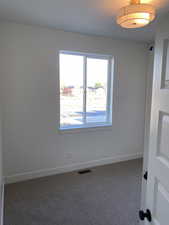 Unfurnished room with baseboards and dark colored carpet