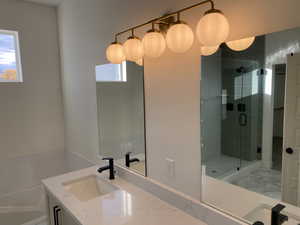 Full bathroom featuring vanity, a bath, a stall shower, and light marble finish floors