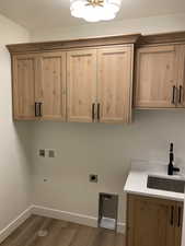 Laundry area featuring dark wood-style floors, a textured ceiling, electric dryer hookup, washer hookup, and cabinet space