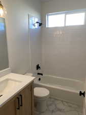 Bathroom featuring vanity, shower / tub combination, and light marble finish flooring