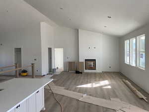 Unfurnished living room featuring high vaulted ceiling and wood finished floors