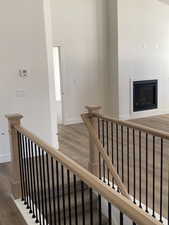 Stairs featuring wood finished floors and a glass covered fireplace