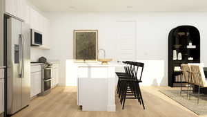 Kitchen with appliances with stainless steel finishes, white cabinets, a center island with sink, light wood-type flooring, and a breakfast bar area