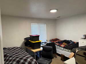 Bedroom featuring light carpet and a textured ceiling