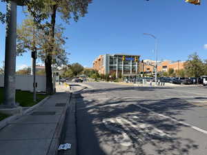 View of asphalt street featuring traffic lights, curbs, street lights, and sidewalks
