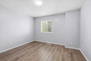 Spare room featuring light wood-style flooring and baseboards