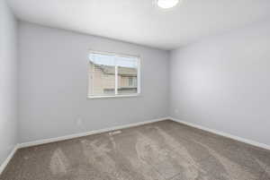 Carpeted spare room featuring baseboards