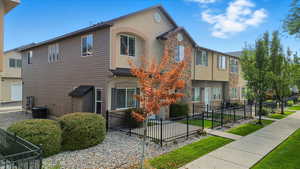 Traditional-style house featuring a fenced front yard, stucco siding, and stone siding