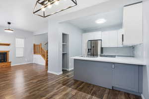 Kitchen featuring white cabinetry, a peninsula, dark wood finished floors, and stainless steel refrigerator with ice dispenser