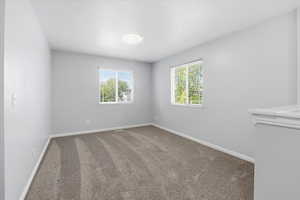 Carpeted empty room featuring healthy amount of natural light
